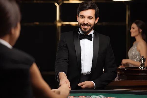 45QBET — Uma experiência de jogos de alto nível sem limites Uma mulher em um vestido verde luxuoso ao lado de uma roleta ornamentada, capturando o clima sofisticado do 45QBET.